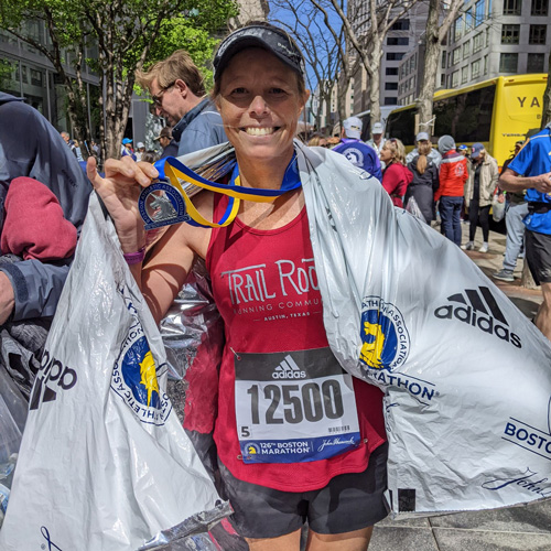 Woman holding up medal after a marathon.